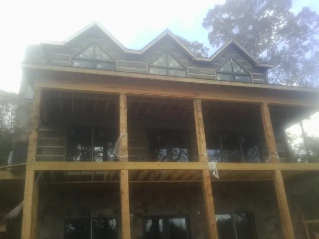 Dormers and porch framing on a large log home under construction — Roof Coating work by our crew in Leland
