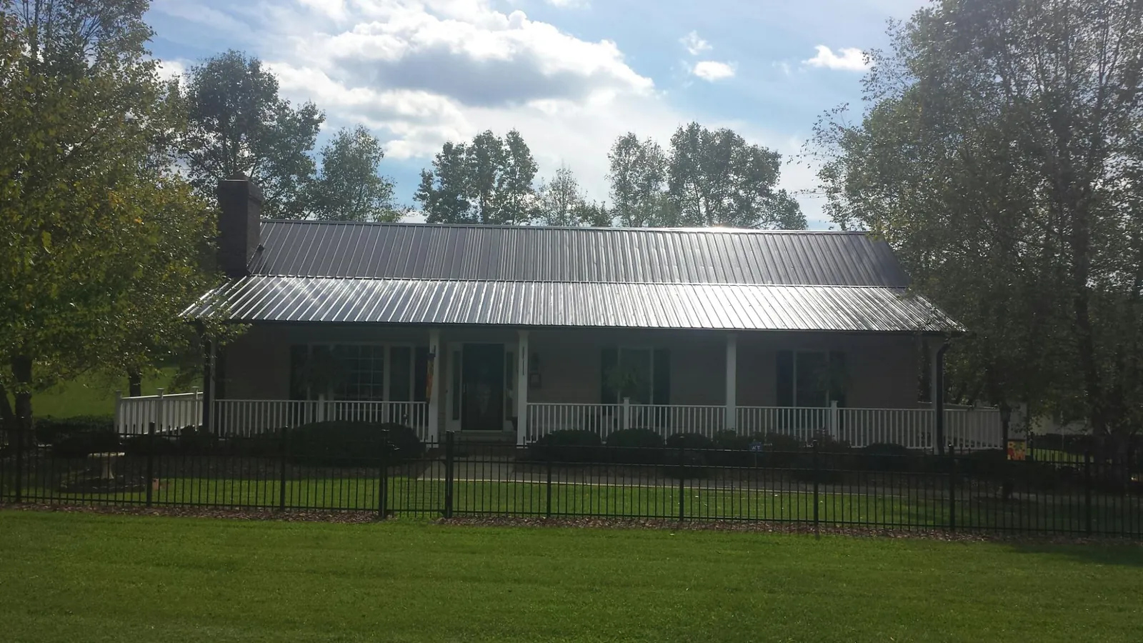 Gray metal roof on a brick ranch with a full width front porch — Gutter Guard Installation work by our crew in Leland