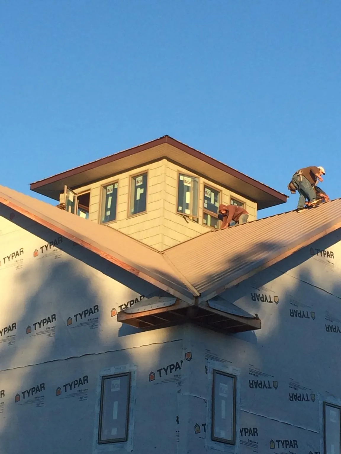 Roofers working around a rooftop cupola on a new metal roof at sunset — Roof Waterproofing in Leland by Roofing Brothers
